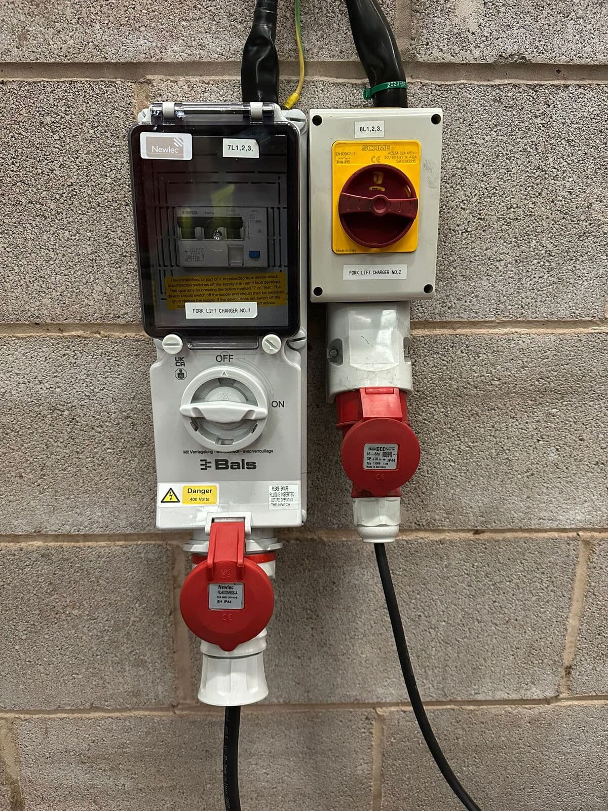 Red industrial sockets and isolators on a block wall