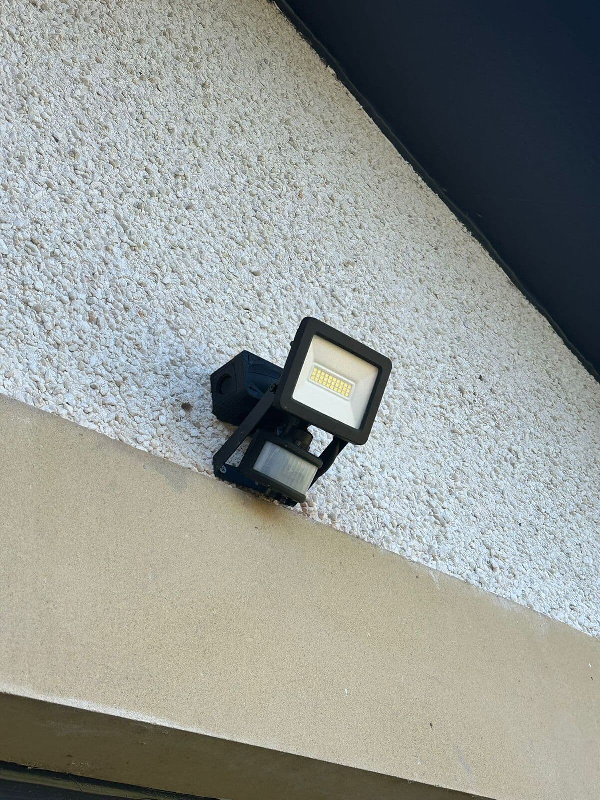 LED floodlight with motion sensor under the eaves of a house