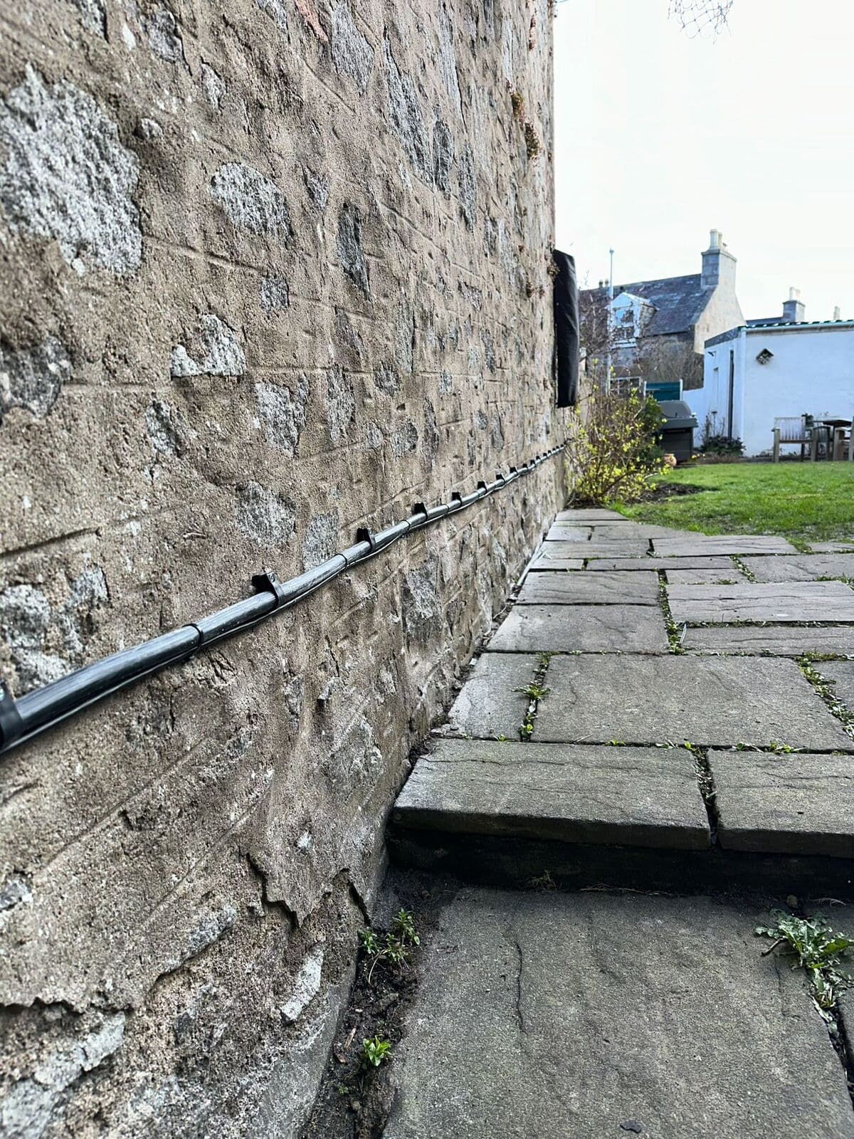 Outside cable run clipped neatly along a stone wall