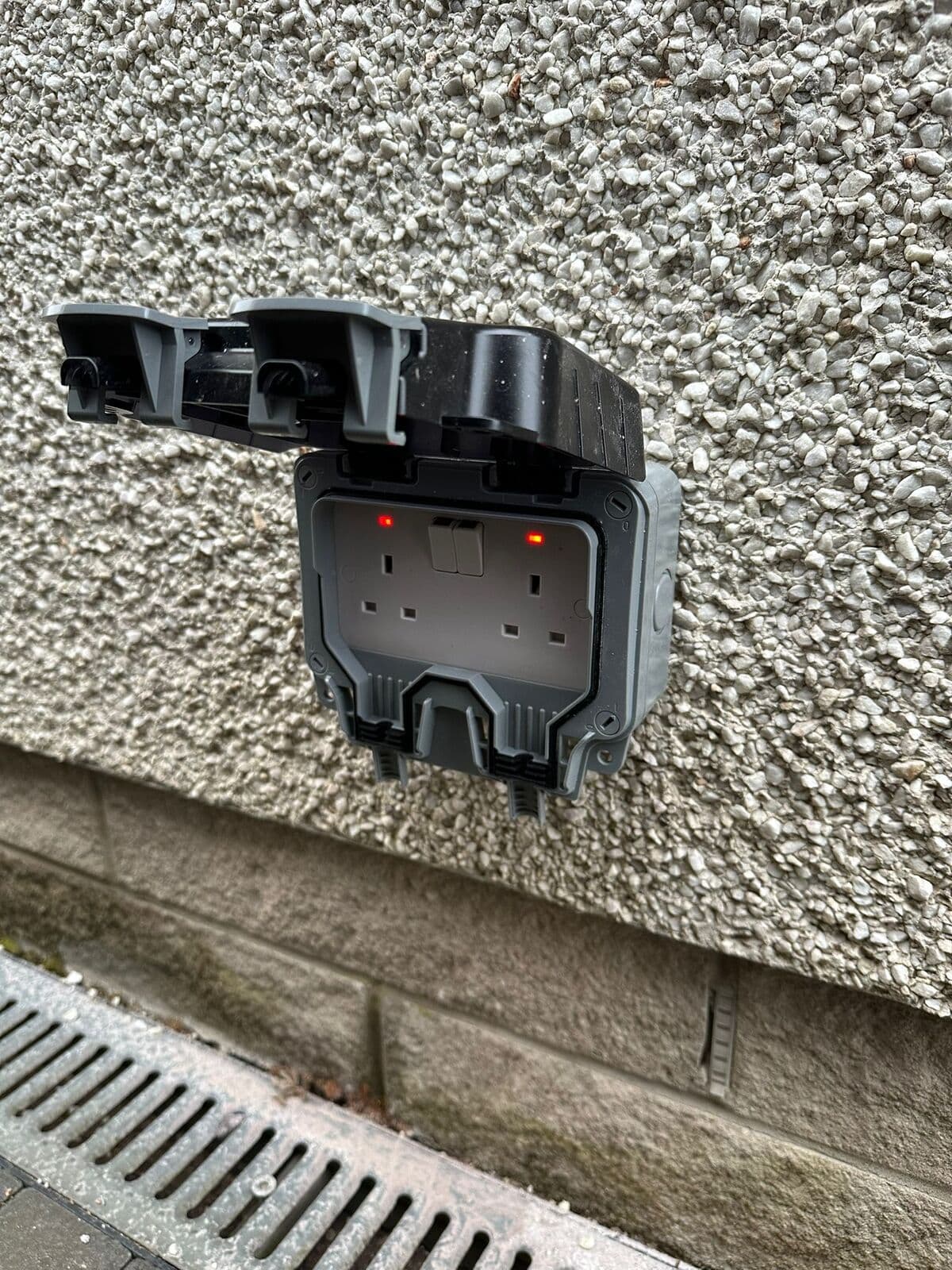 Weatherproof double socket fitted on a roughcast wall
